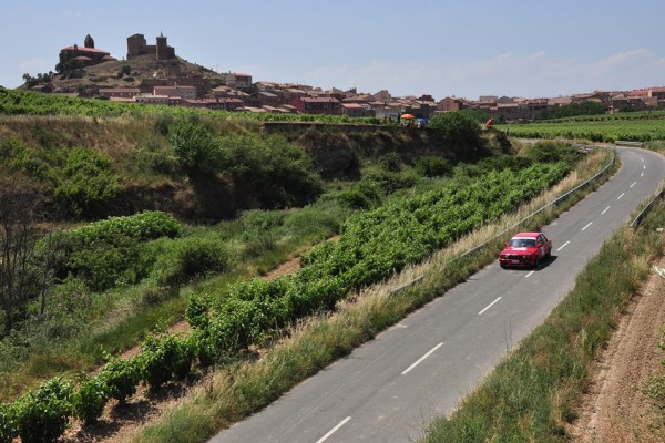 Coche de rally rojo al fondo el castillo de San Vicente de la Sonsierra
